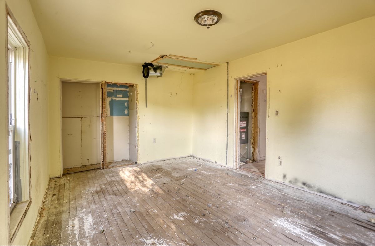 Bedroom before: stripped walls, open framing and damaged floor