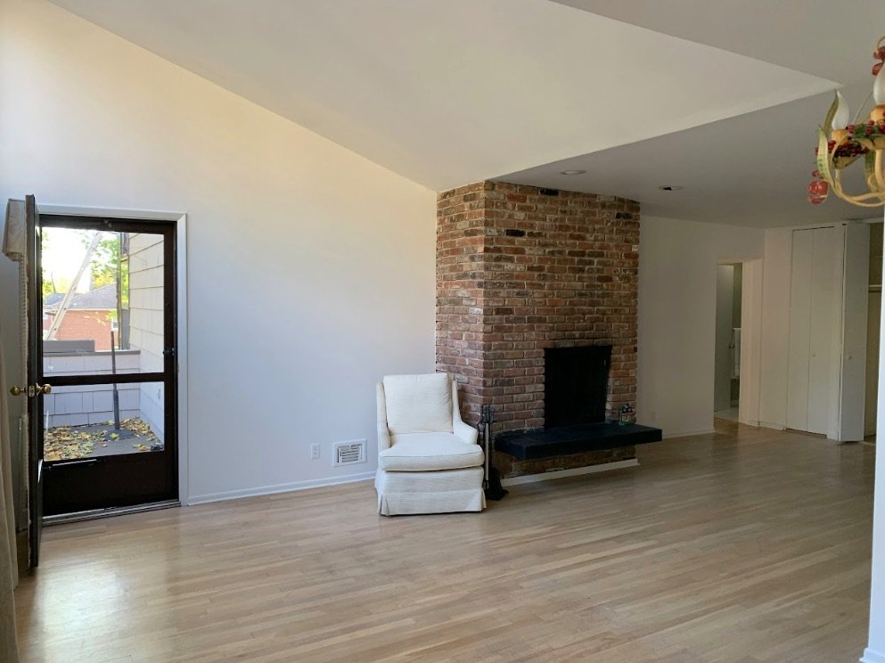 Living room with brick fireplace, freshly painted walls and ceiling